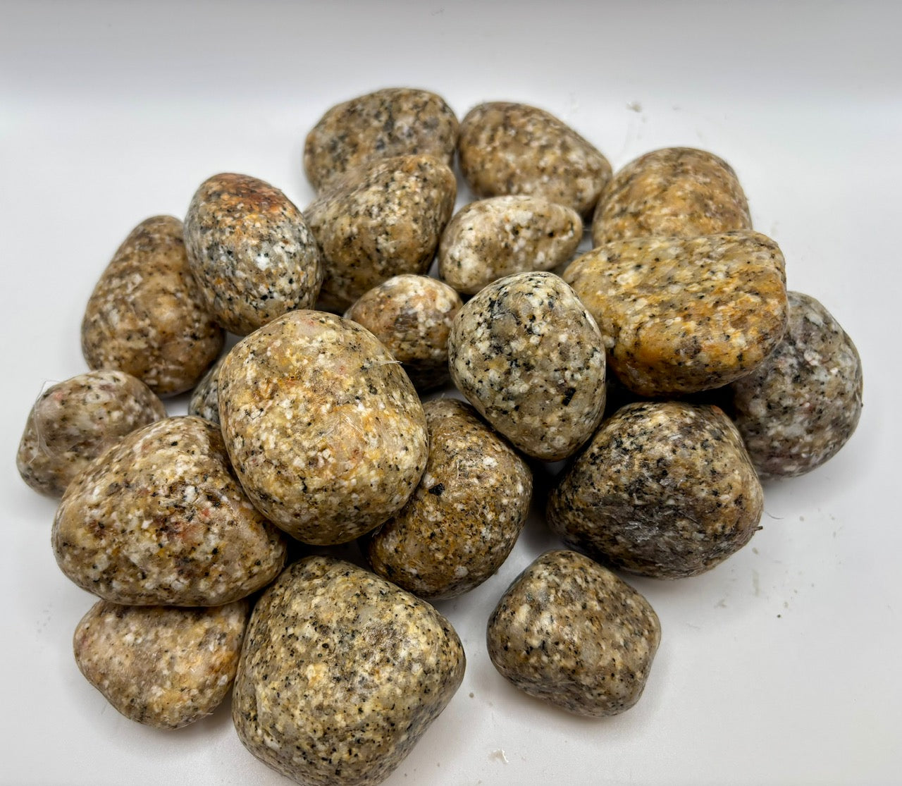 Pile of round, Gold and Black Granite stones on a white background